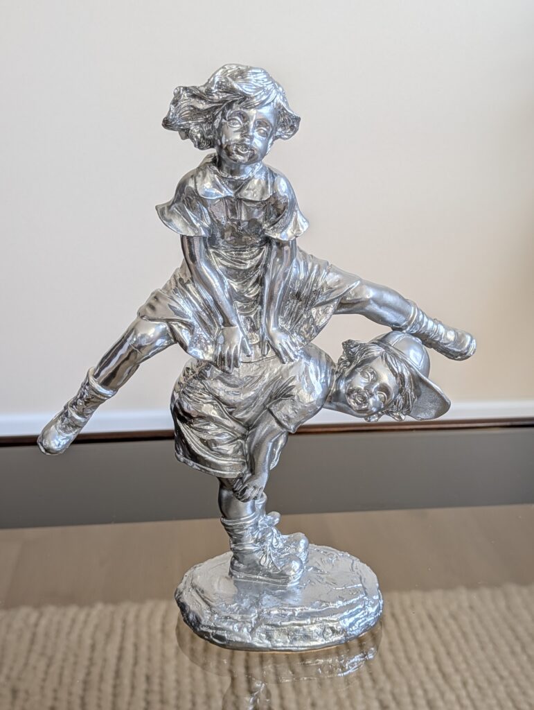 Statuette en plâtre "enfants jouant à saute-mouton" fabriquée entre 1950 et 1980. Son sujet de style dit "classique" et sa modernisation avec une peinture chromée en font une pièce hors catégorie et remarquable.